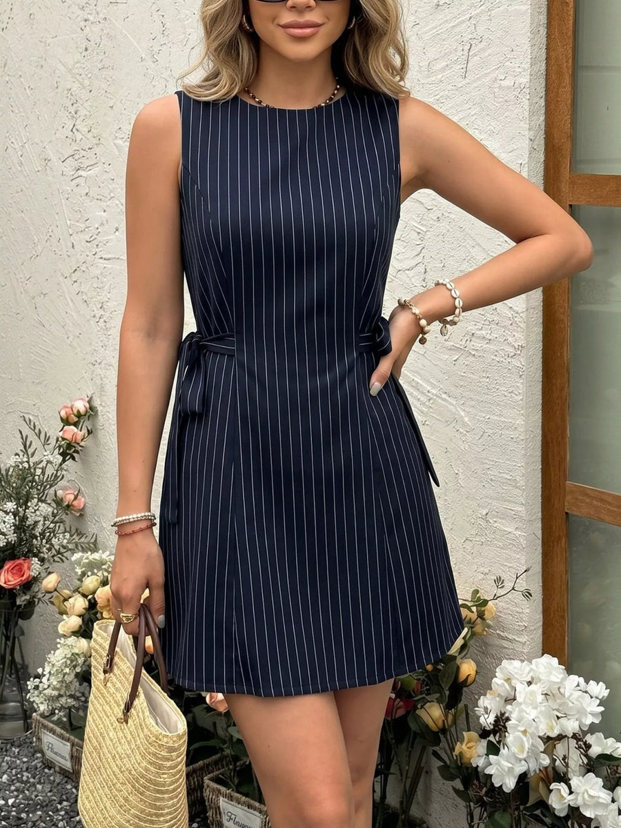 Woman wearing a navy pinstripe dress with a white background and decorative elements.