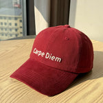 Red cap with 'Carpe Diem' text on a wooden surface