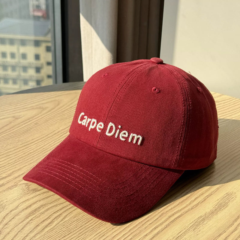 Red cap with 'Carpe Diem' text on a wooden surface