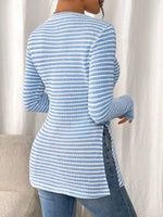 Person wearing a blue and white striped sweater against a white curtain background