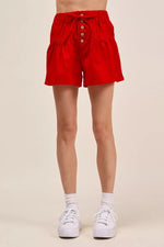 Red shorts worn by a person on a beige background
