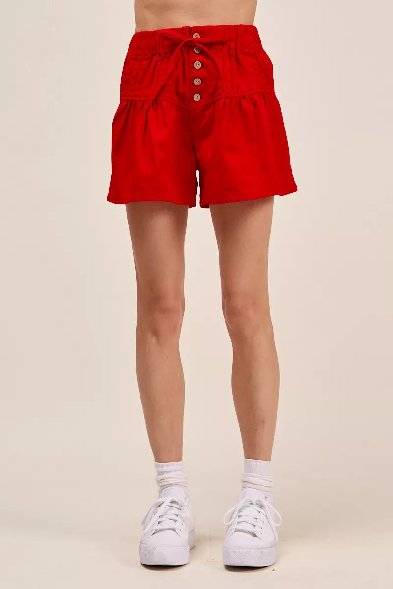 Red shorts worn by a person on a beige background