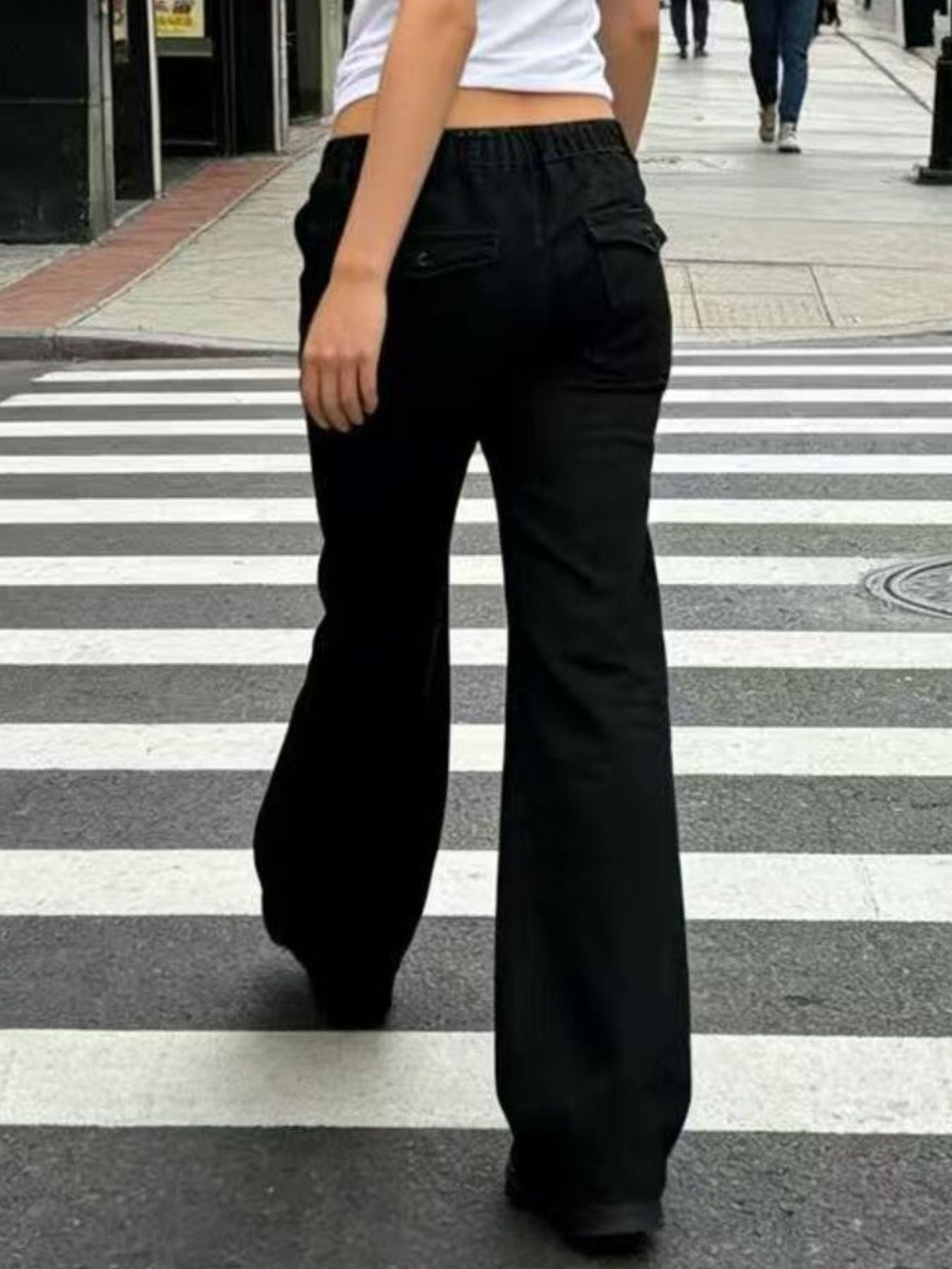 Person wearing black wide-leg pants crossing a zebra crossing.