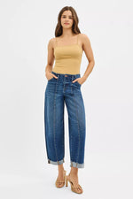 Woman wearing a beige top and blue jeans on a white background