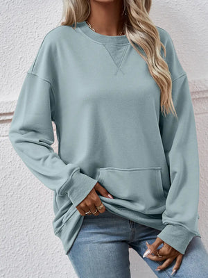 Person wearing a light blue sweatshirt and jeans against a white wall