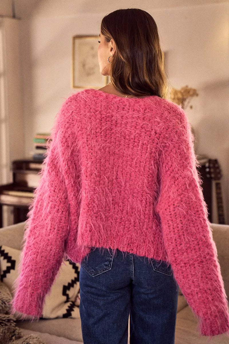Person wearing a pink fuzzy sweater in a living room setting