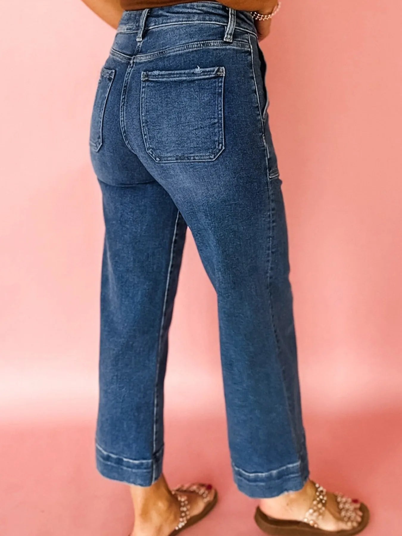 Blue jeans worn by a person on a pink background