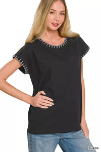 Woman wearing a black top with white trim on a white background