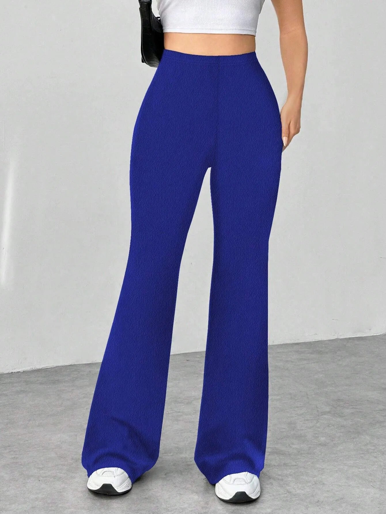Blue wide-leg pants worn by a person on a gray floor with a white wall background