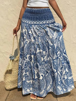 Person wearing a blue and white patterned skirt holding a straw bag against a beige wall.