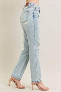 Light blue jeans with a distressed look worn by a person on a beige background