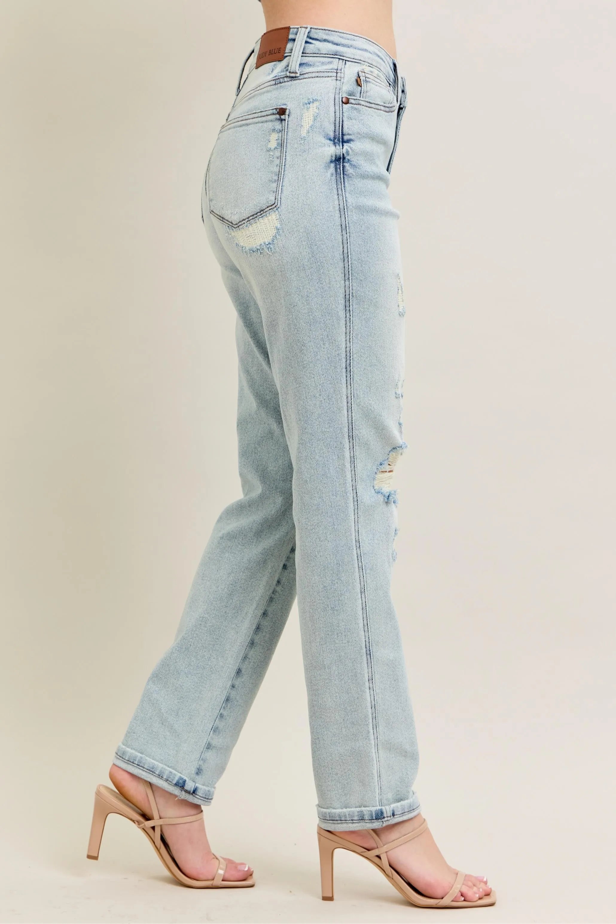 Light blue jeans with a distressed look worn by a person on a beige background
