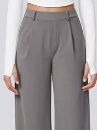 Gray pleated pants worn by a person on a white background