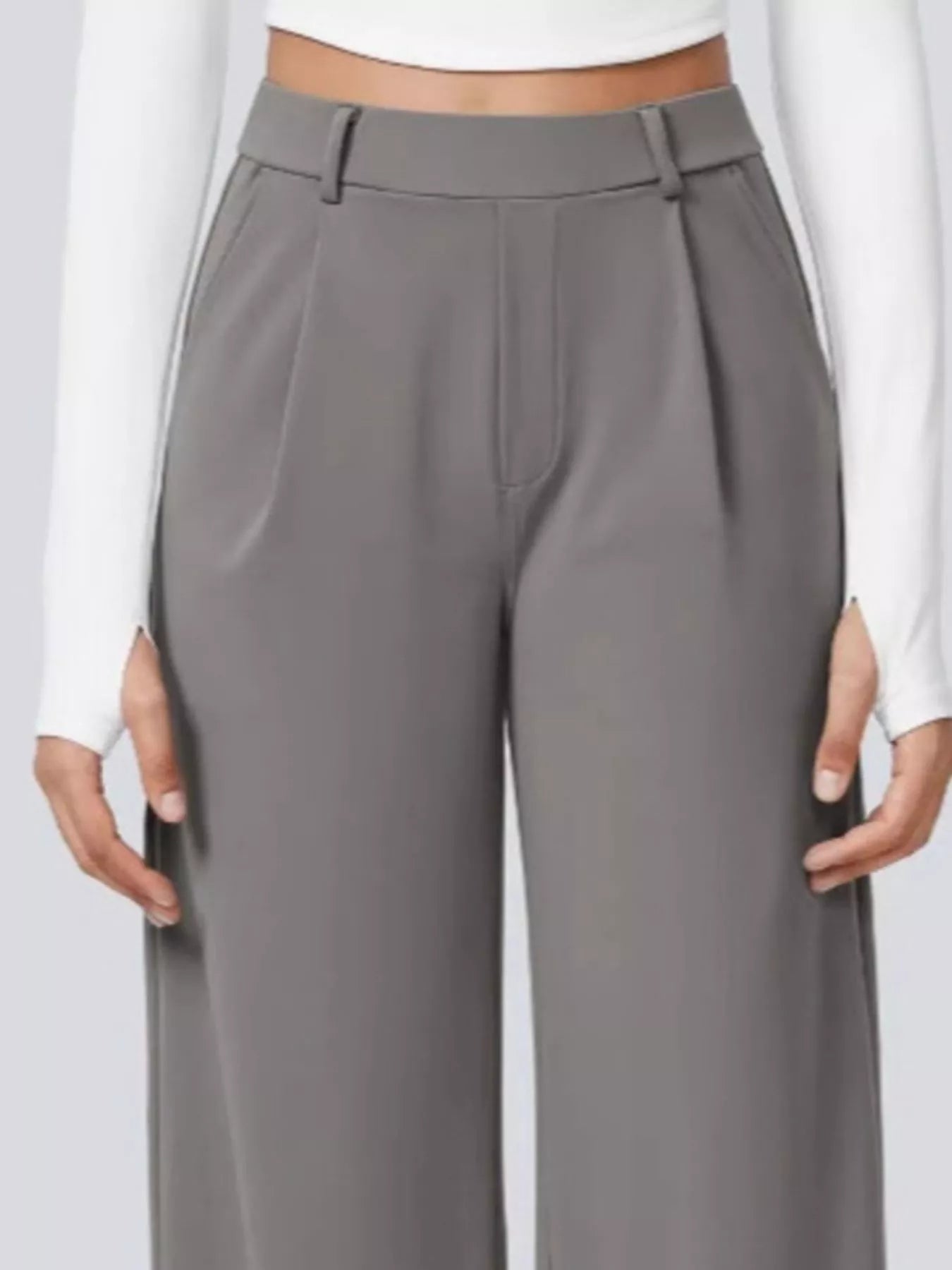 Gray pleated pants worn by a person on a white background