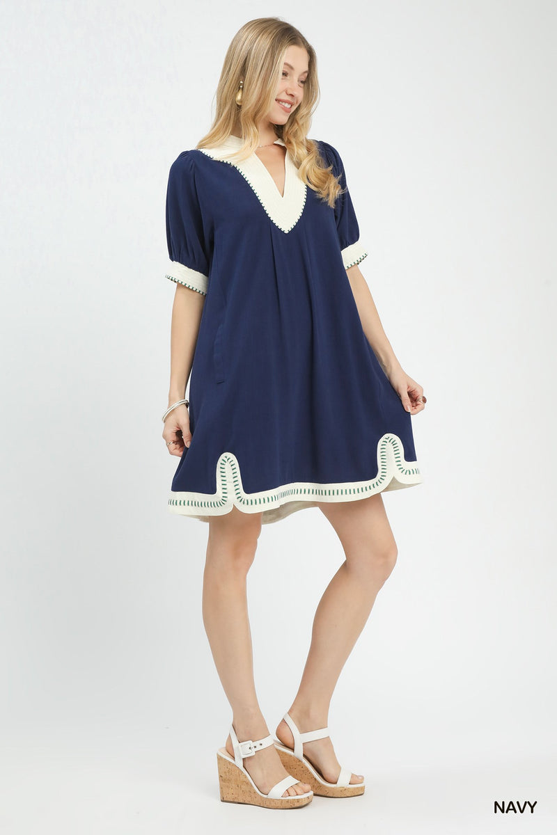 Woman wearing a navy dress with white trim on a white background