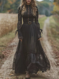 Woman in a long black lace dress standing on a dirt path in a natural setting