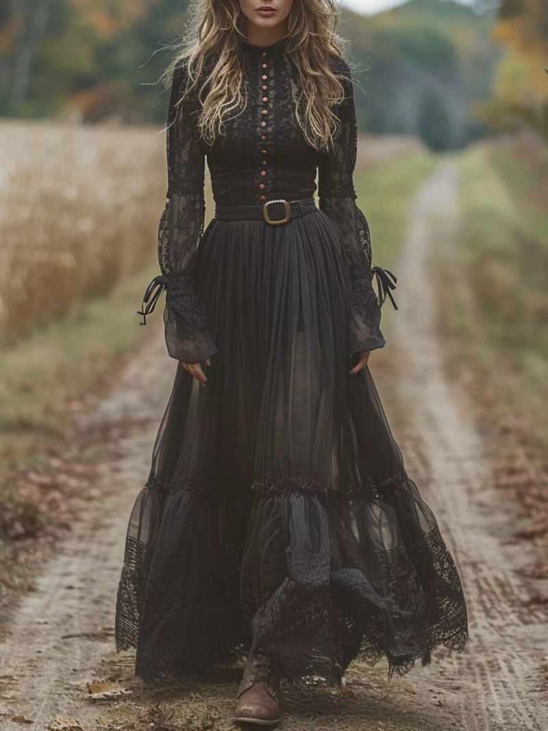 Woman in a long black lace dress standing on a dirt path in a natural setting