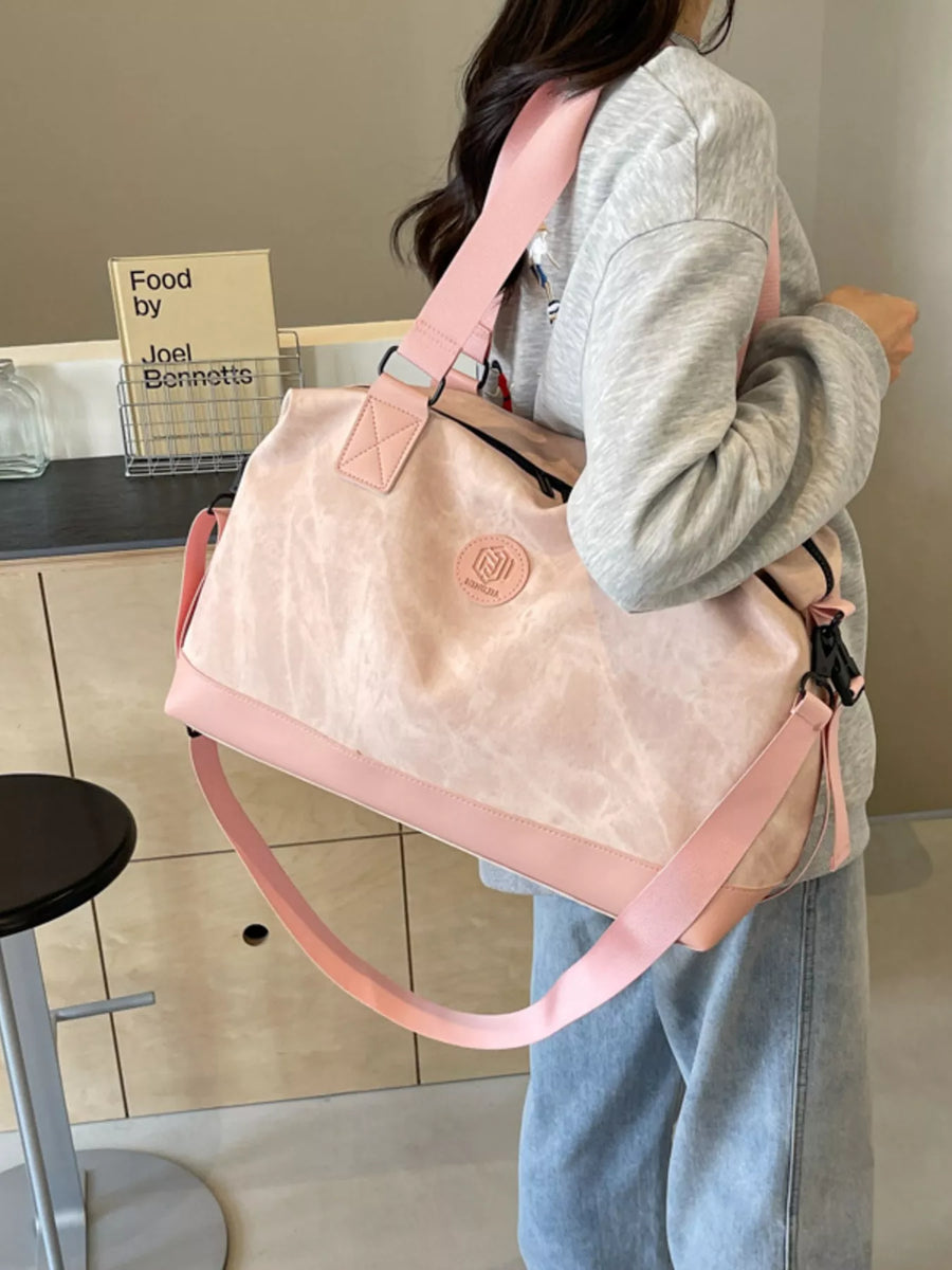 Person holding a beige and pink handbag in a kitchen setting