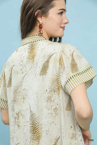 Woman wearing a beige and brown patterned blouse against a light blue background