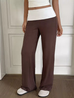 Person wearing brown wide-leg pants and a white top against a neutral background