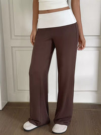 Person wearing brown wide-leg pants and a white top against a neutral background