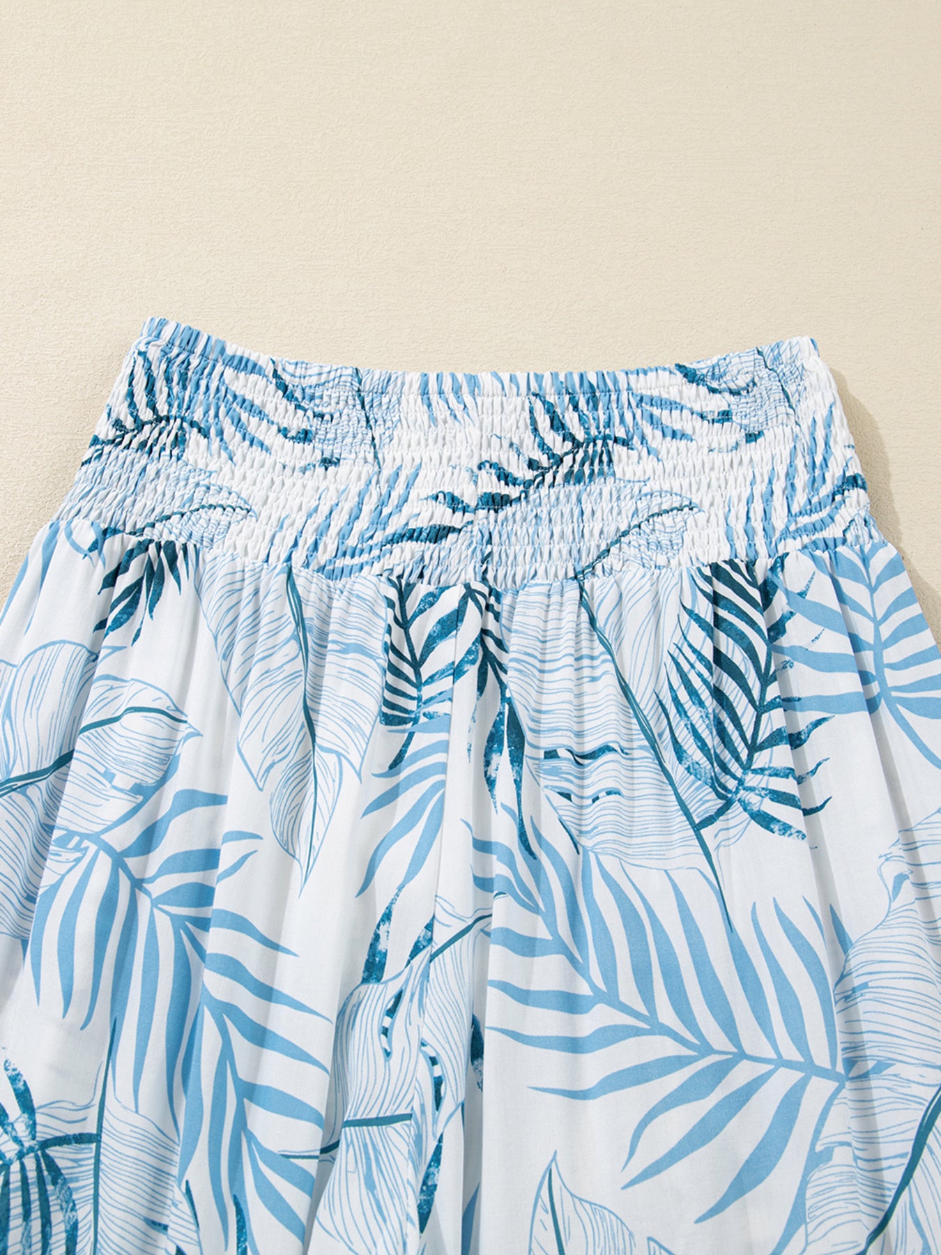 Blue leaf patterned pants on a beige background