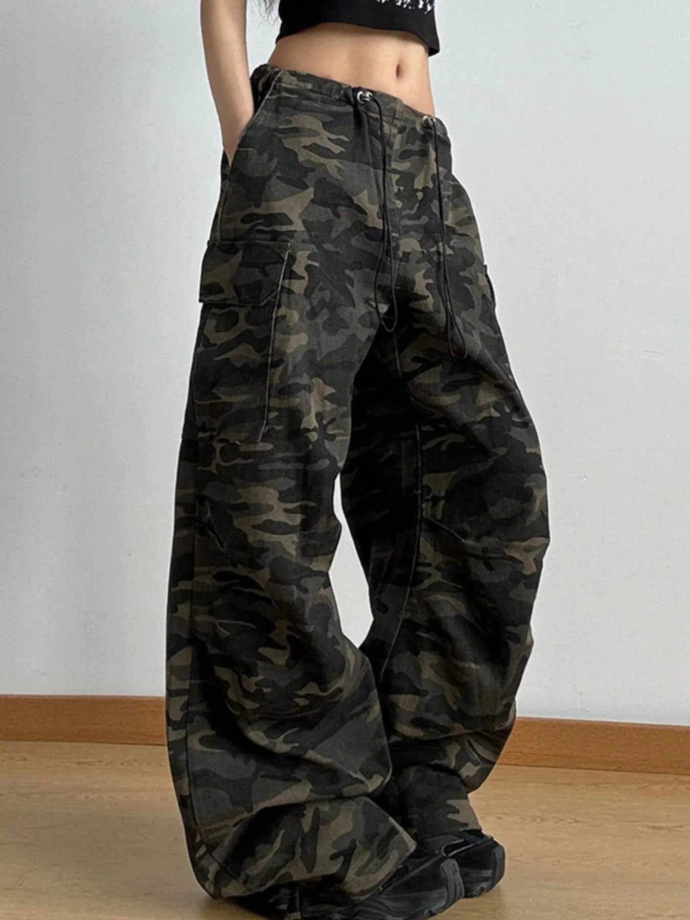 Camouflage pants worn by a person on a plain background
