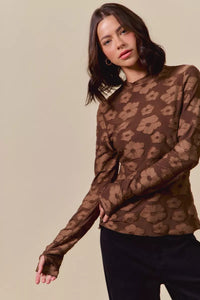 Woman wearing a sheer brown leopard print top against a beige background