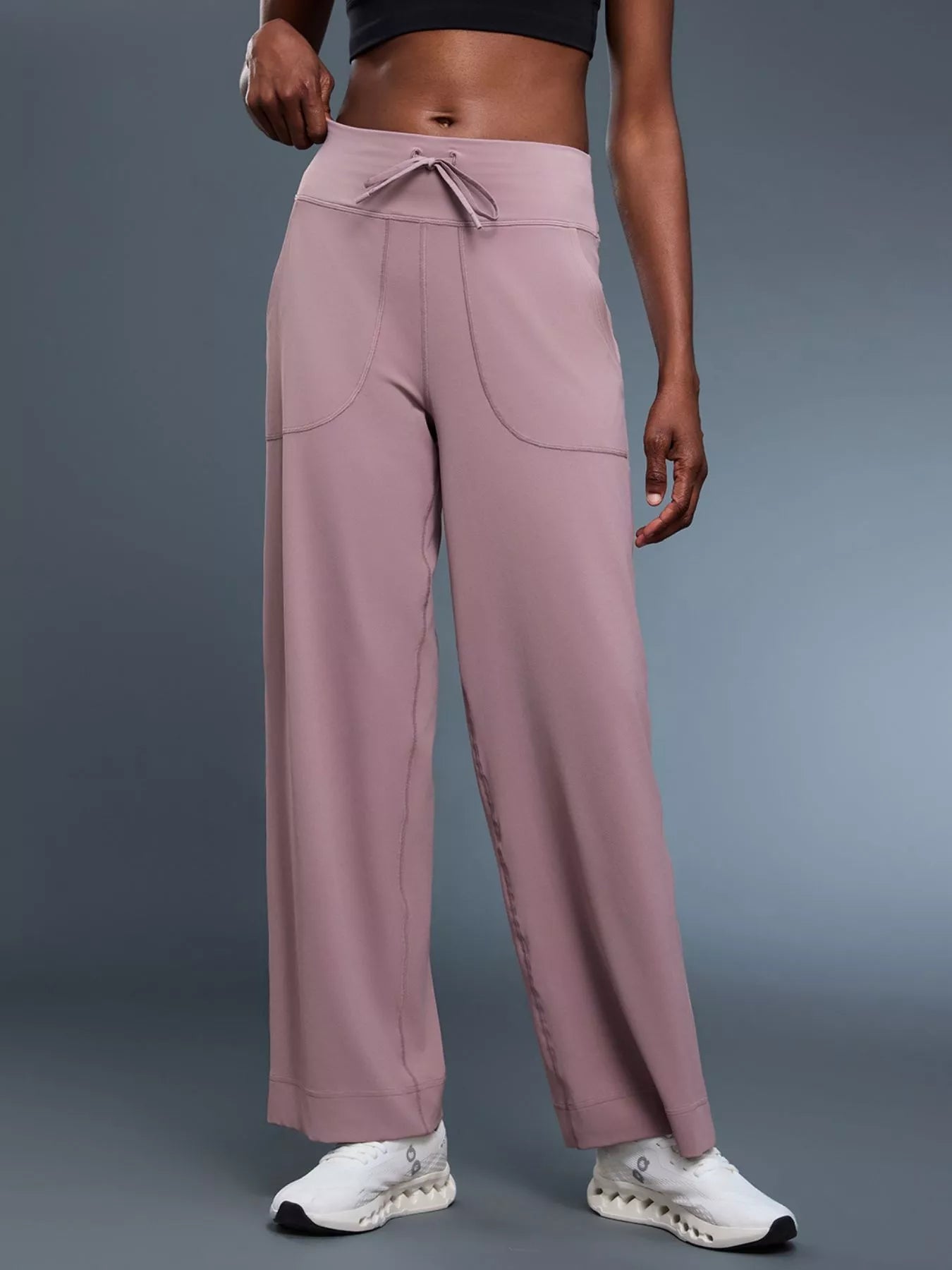 Person wearing mauve high-waisted pants with a gray background