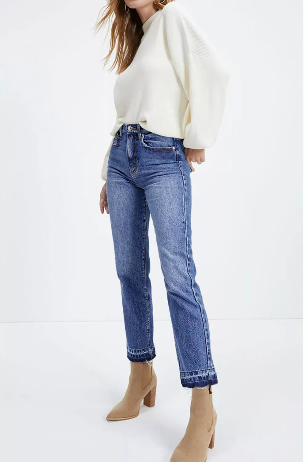 Person wearing a white sweater and blue jeans on a white background