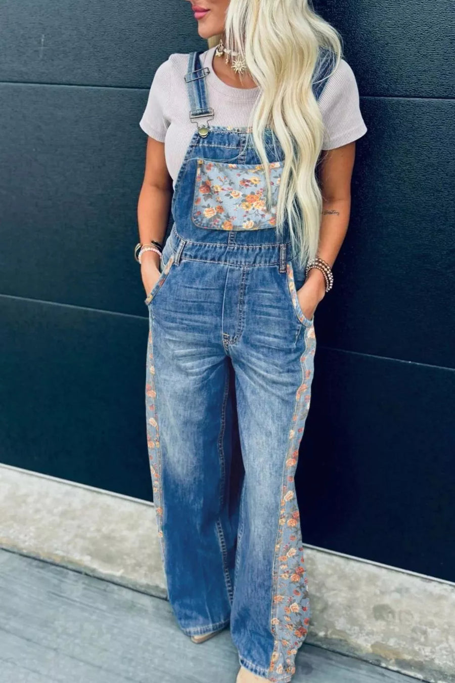 Person wearing a floral denim overalls with a plain background