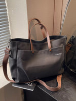 Gray tote bag with brown straps on a surface