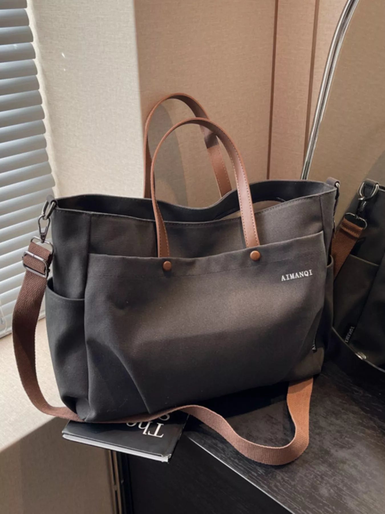 Gray tote bag with brown straps on a surface
