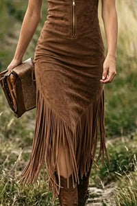 Brown suede dress with fringe and matching clutch held by a person in a natural setting
