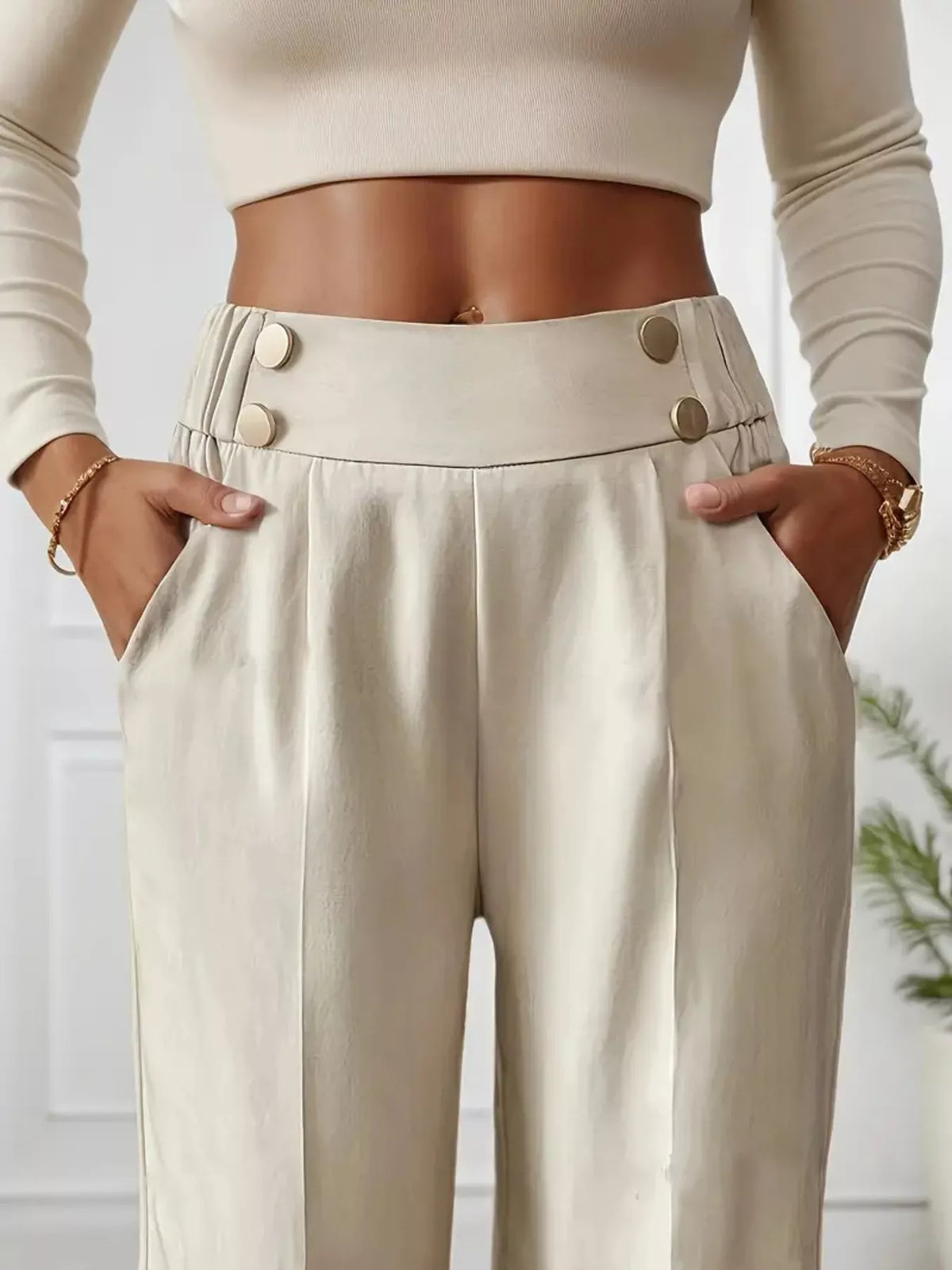 Person wearing beige high-waisted pants with button details and a cropped top.
