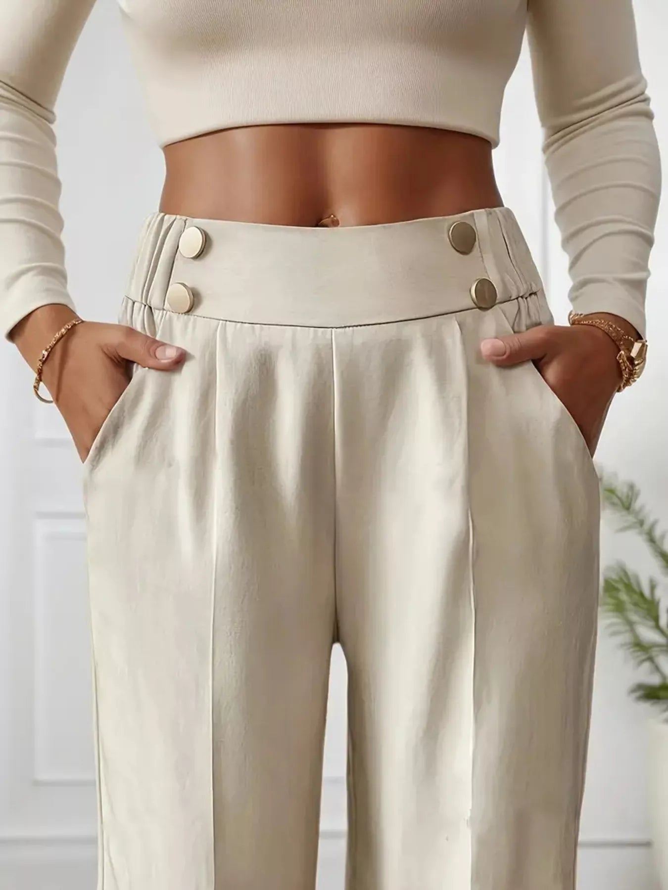 Person wearing beige high-waisted pants with button details and a cropped top.