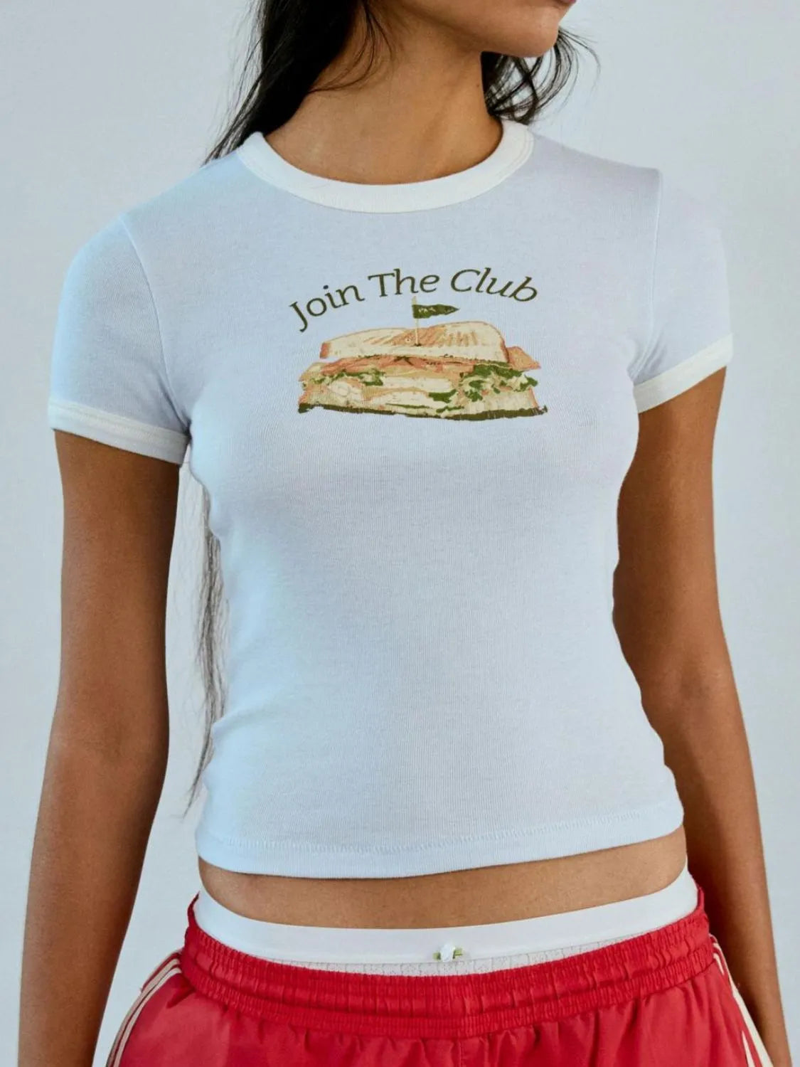Person wearing a light blue t-shirt with a graphic and text 'Join The Club' on a plain background