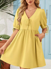 Woman wearing a yellow dress with a blue door in the background