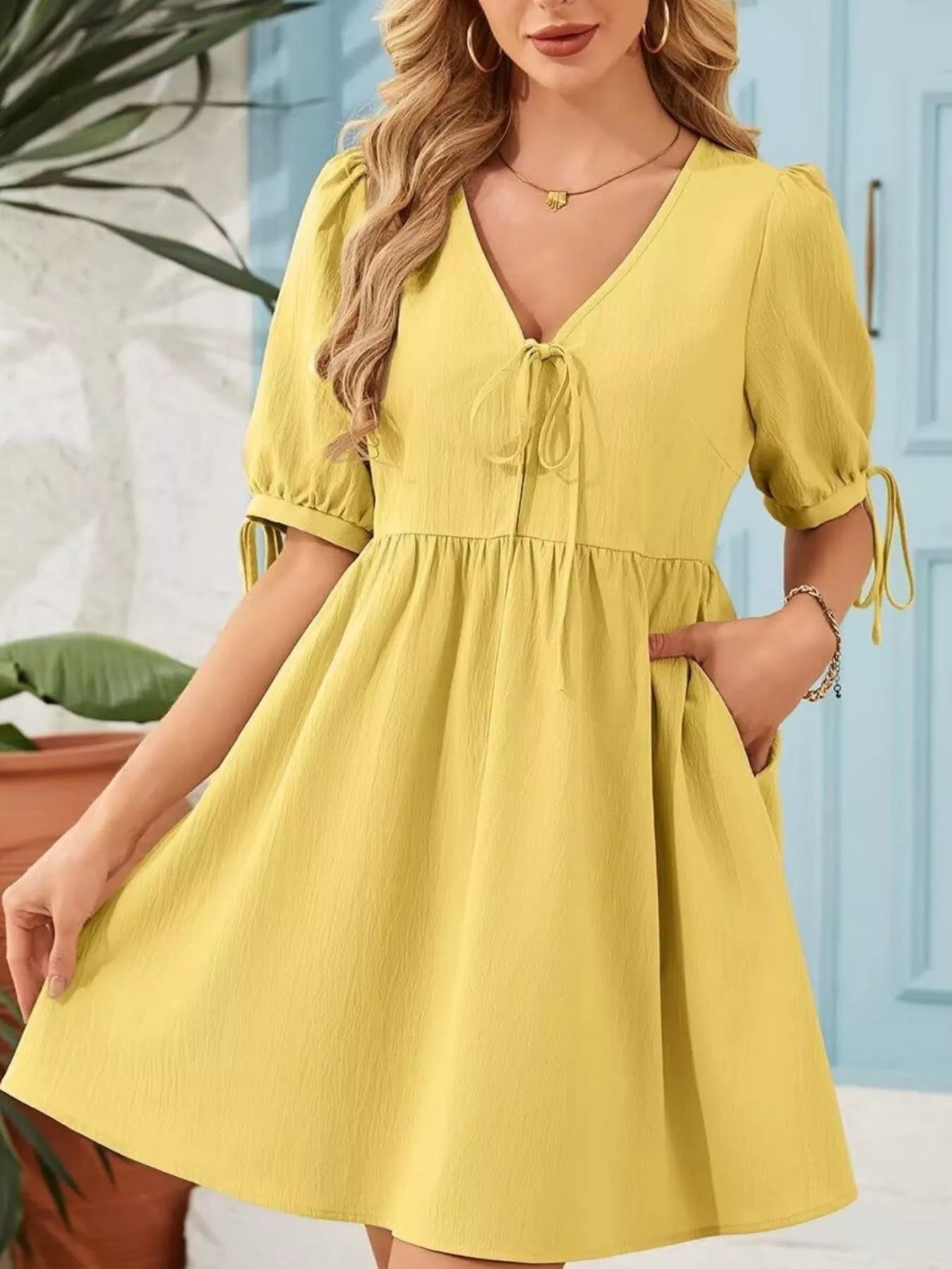 Woman wearing a yellow dress with a blue door in the background