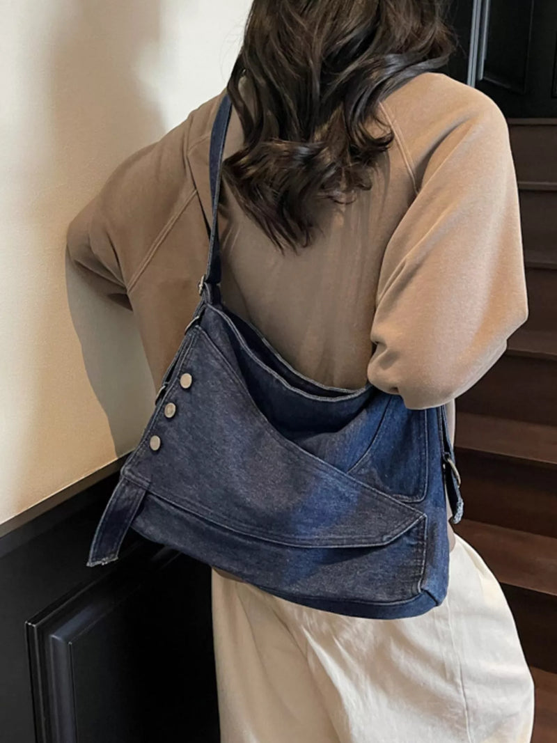 Person wearing a blue denim bag over one shoulder indoors.