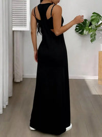 Woman wearing a black dress in a room with a plant and curtain.