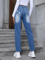 Person wearing blue jeans and white sneakers standing on steps.