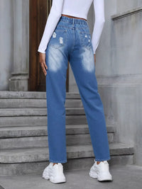 Person wearing blue jeans and white sneakers standing on steps.