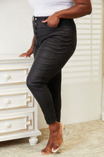 Person wearing black pants with buttons in a room with a white dresser.