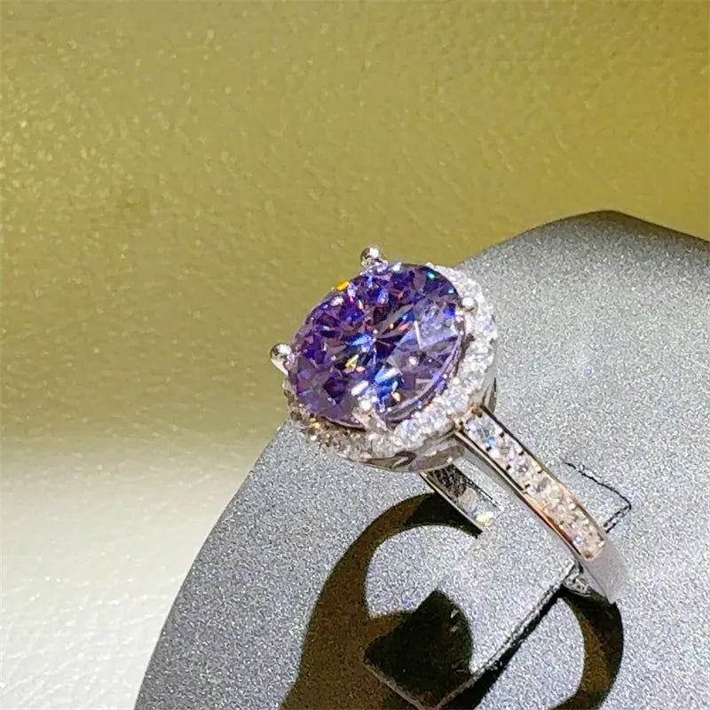 Purple gemstone ring with diamond accents on a gray stand against a yellow background