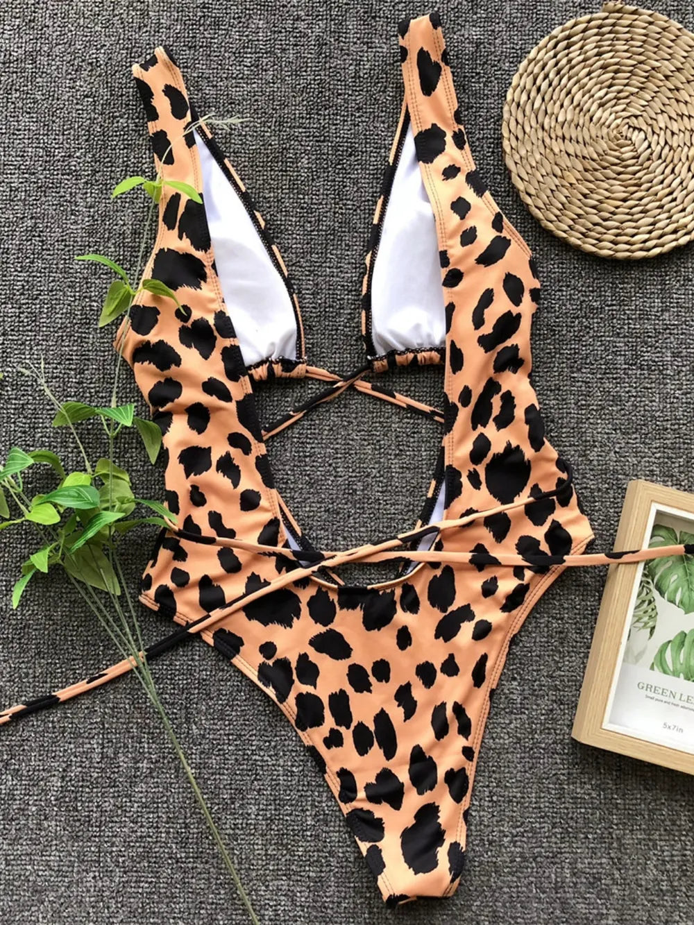 Leopard print bikini set on a textured surface with a plant and woven basket in the background.