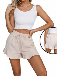 Woman wearing a white crop top and beige shorts on a white background