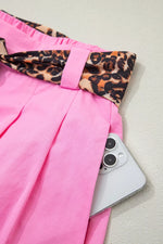 Pink pants with leopard print trim and a phone on a light background