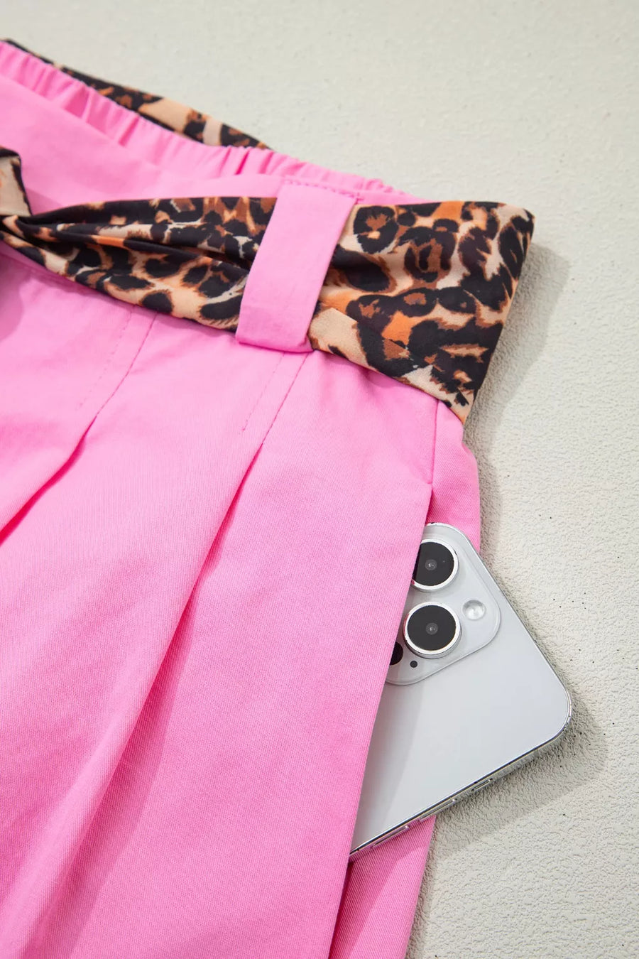 Pink pants with leopard print trim and a phone on a light background
