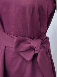 Close-up of a maroon dress with a bow detail on a white background